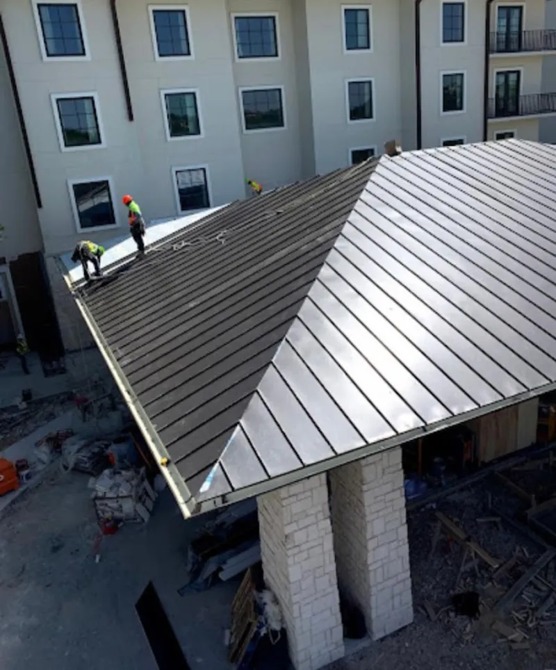 Crew installing standing seam metal roof panels on a commercial project in Rock Springs